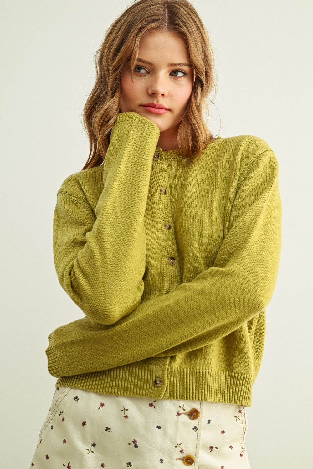 Woman wearing a green sweater with a plain background