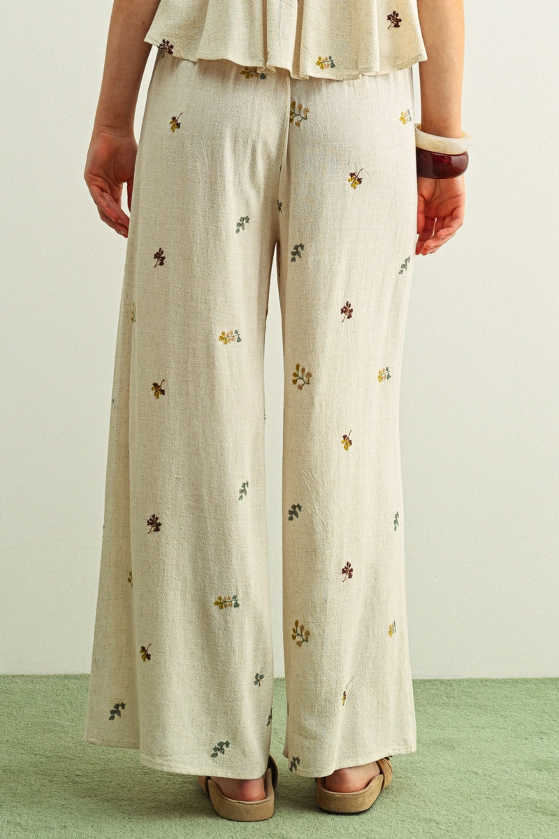 Person wearing beige floral pants on a plain background