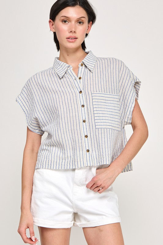 Woman wearing a striped button down blouse against a white background