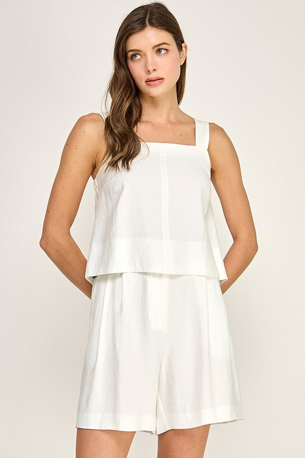 Woman wearing a white sleeveless dress against a plain background
