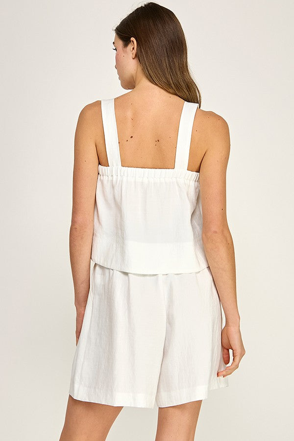 Woman wearing a white dress with thin straps on a plain background