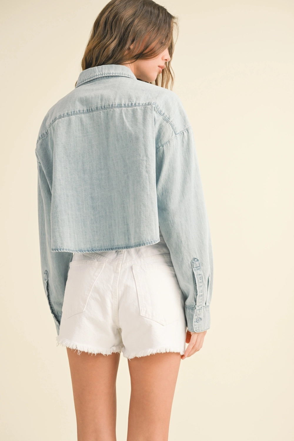 Light blue denim jacket worn by a person on a beige background