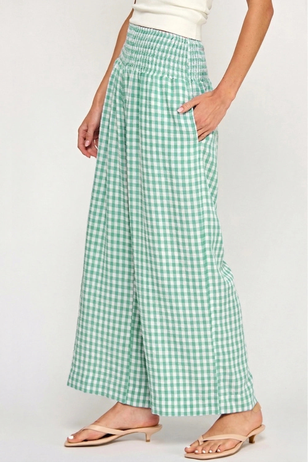Green and white checkered pants worn by a person on a plain background