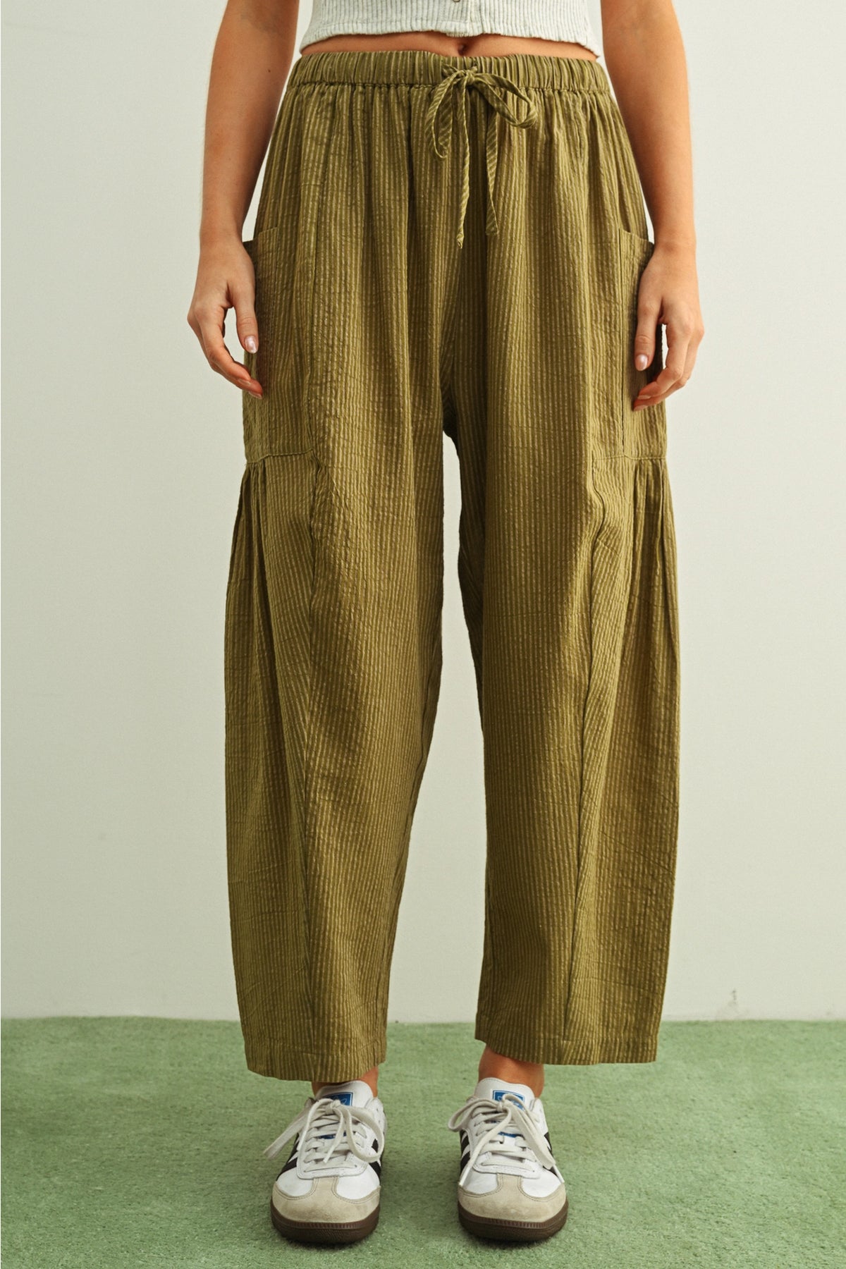 Person wearing olive green pants with a white background