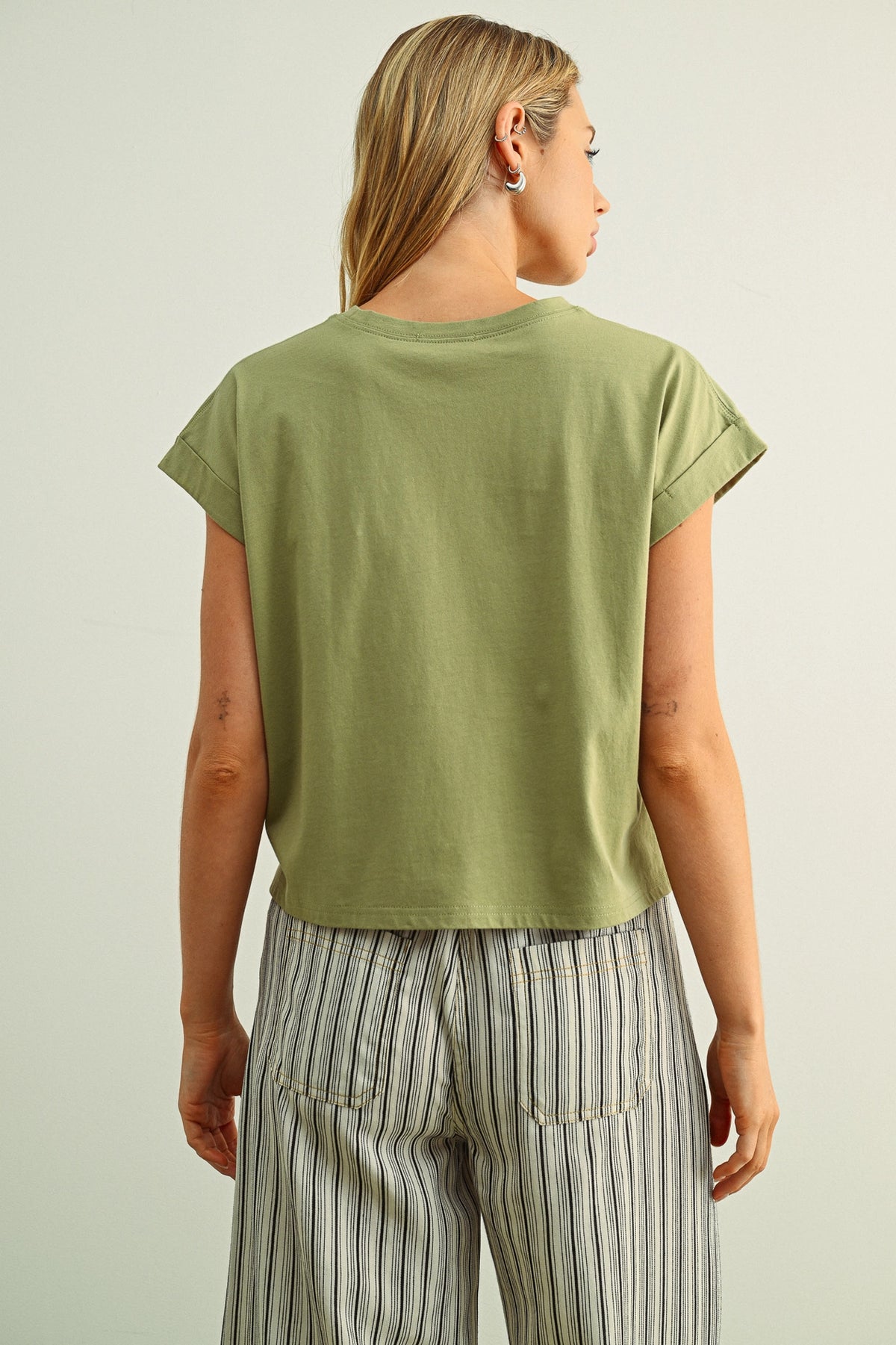 Person wearing a green t-shirt and striped pants on a plain background