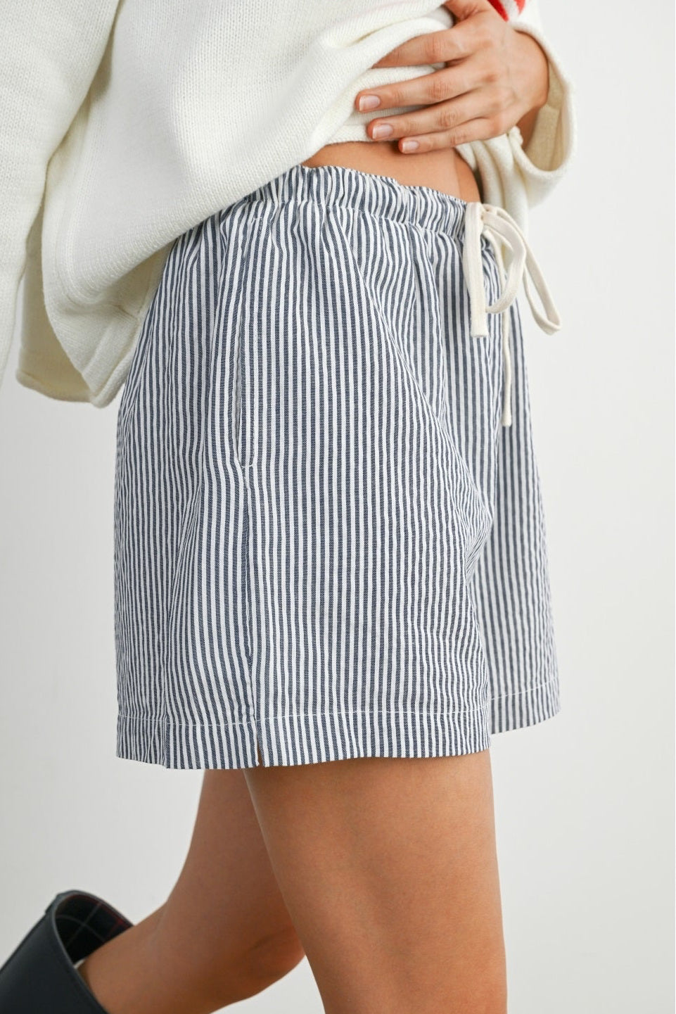 Person wearing a blue and white striped skirt on a plain background