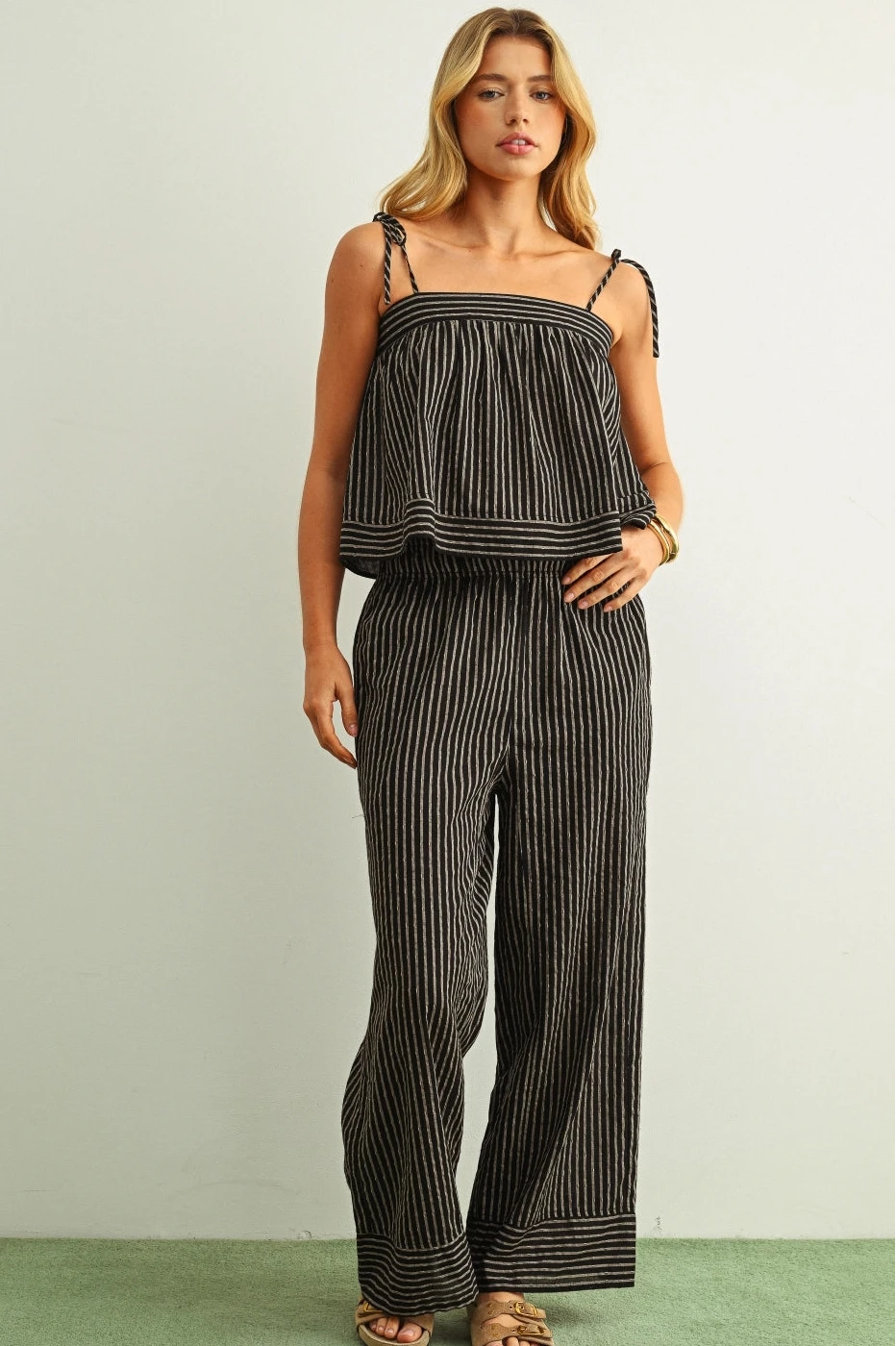 Woman wearing a black and white striped jumpsuit on a plain background