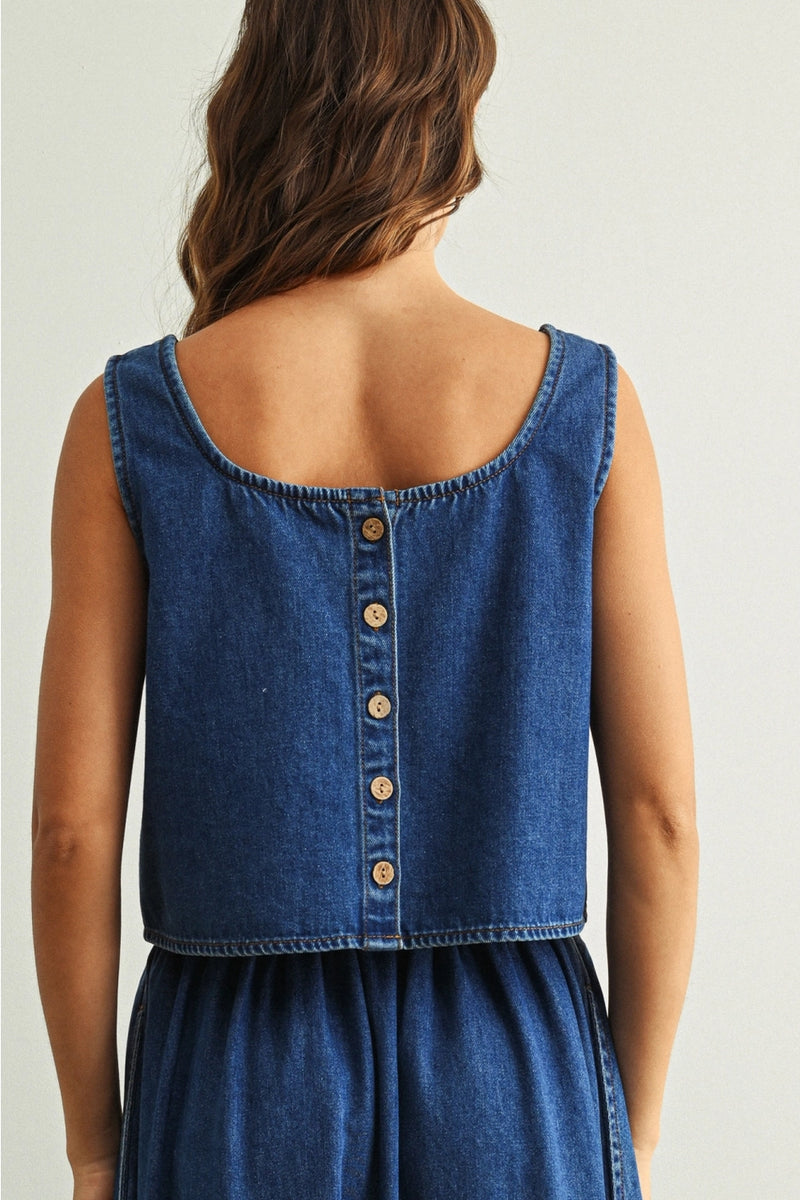 Blue denim blouse with button details on a plain background