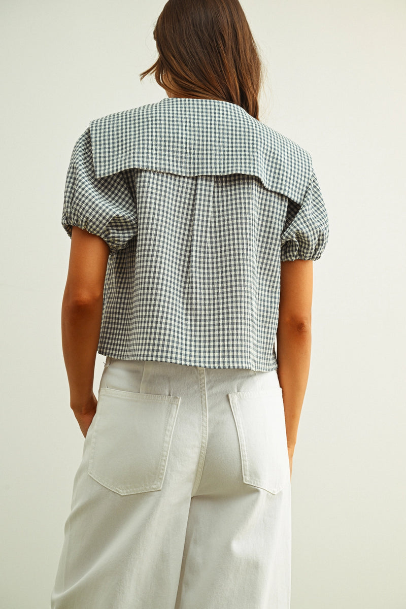 Person wearing a checkered shirt and light-colored pants on a plain background