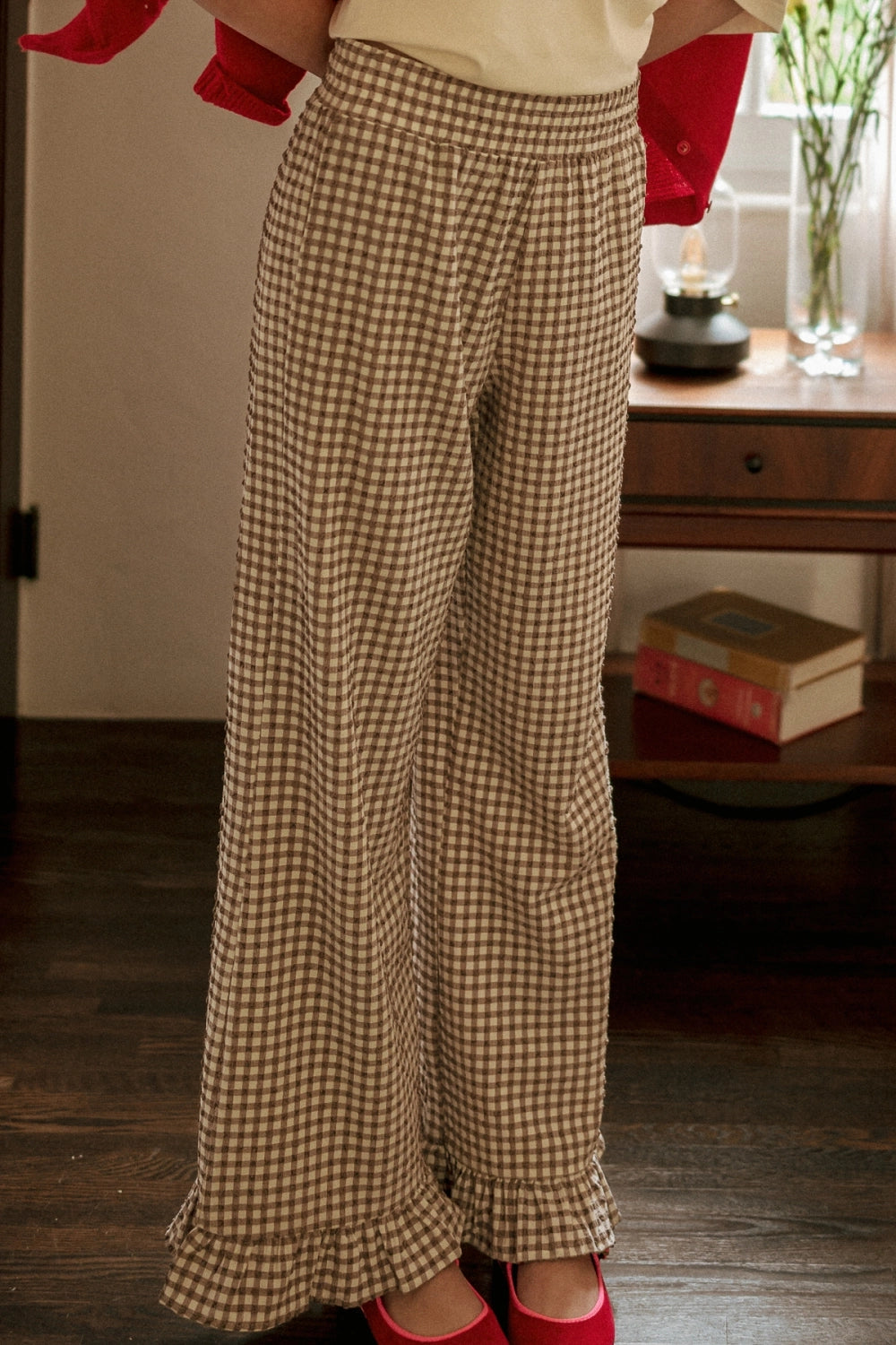 Person wearing checkered pants with a blurred indoor background
