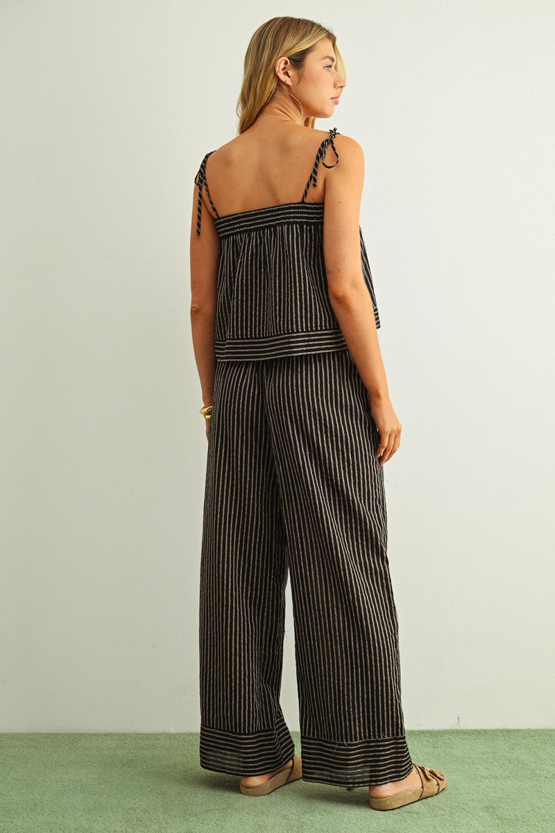 Woman wearing a black and white striped jumpsuit against a plain background