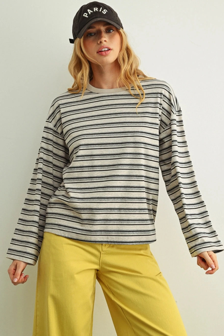 Woman wearing a striped long-sleeve shirt and yellow pants against a plain background