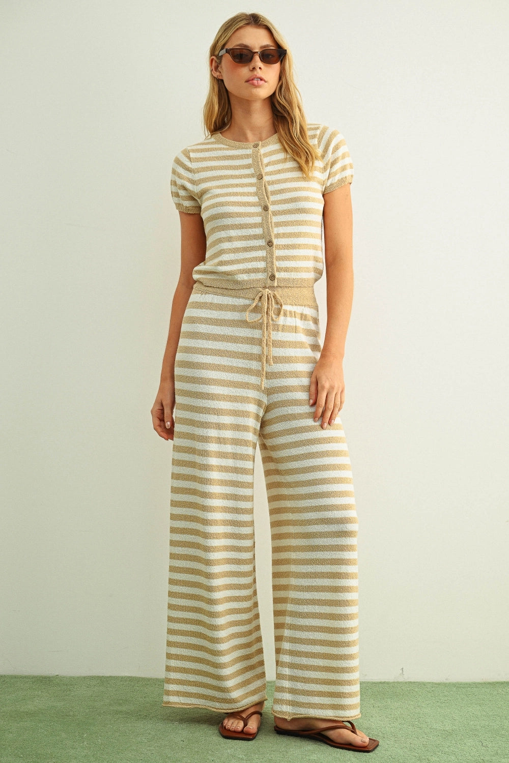 Woman wearing a yellow and white striped outfit on a plain background