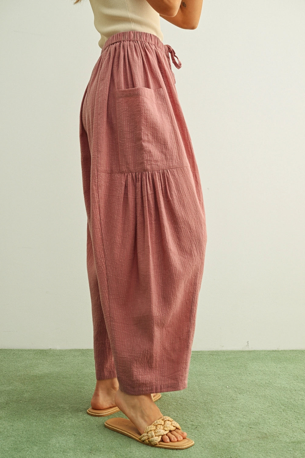 Person wearing pink pants on a green floor with a white wall background