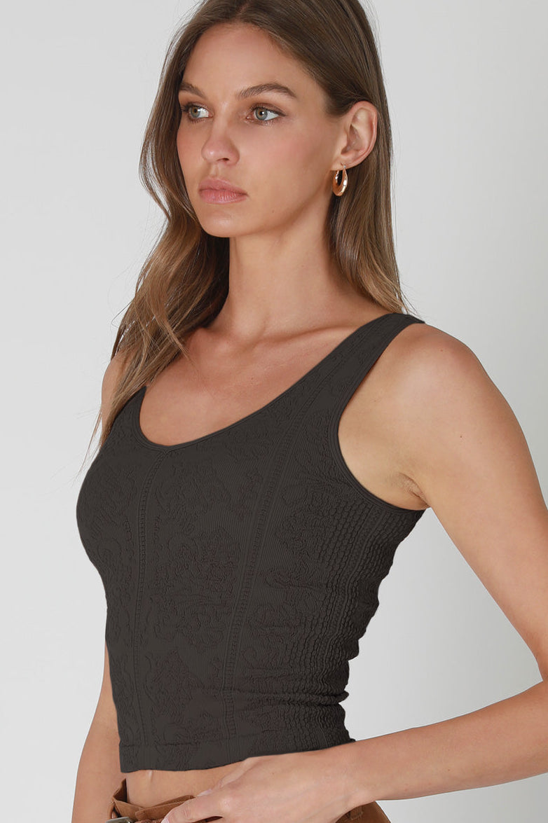 Woman wearing a black tank top against a plain background