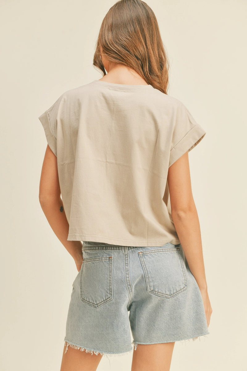 Person wearing a beige top and denim shorts on a plain background