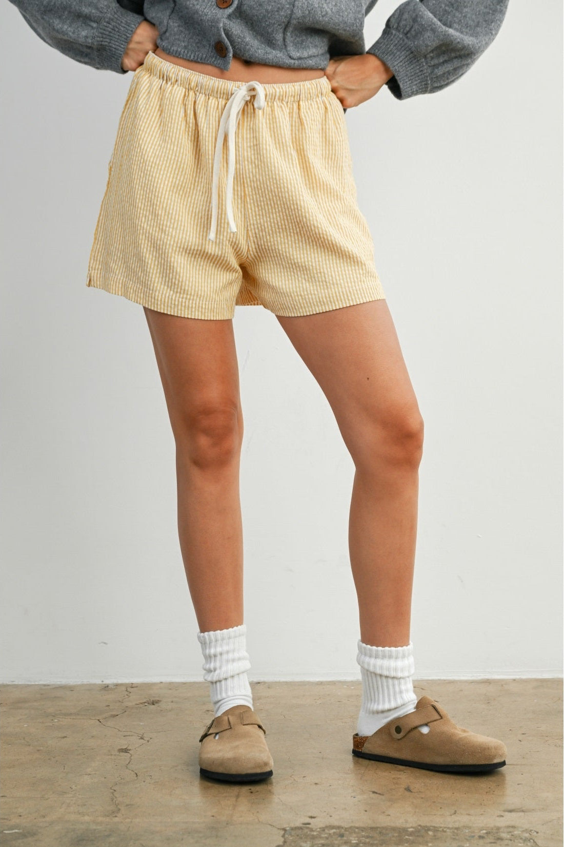 Person wearing yellow shorts and brown shoes on a plain background