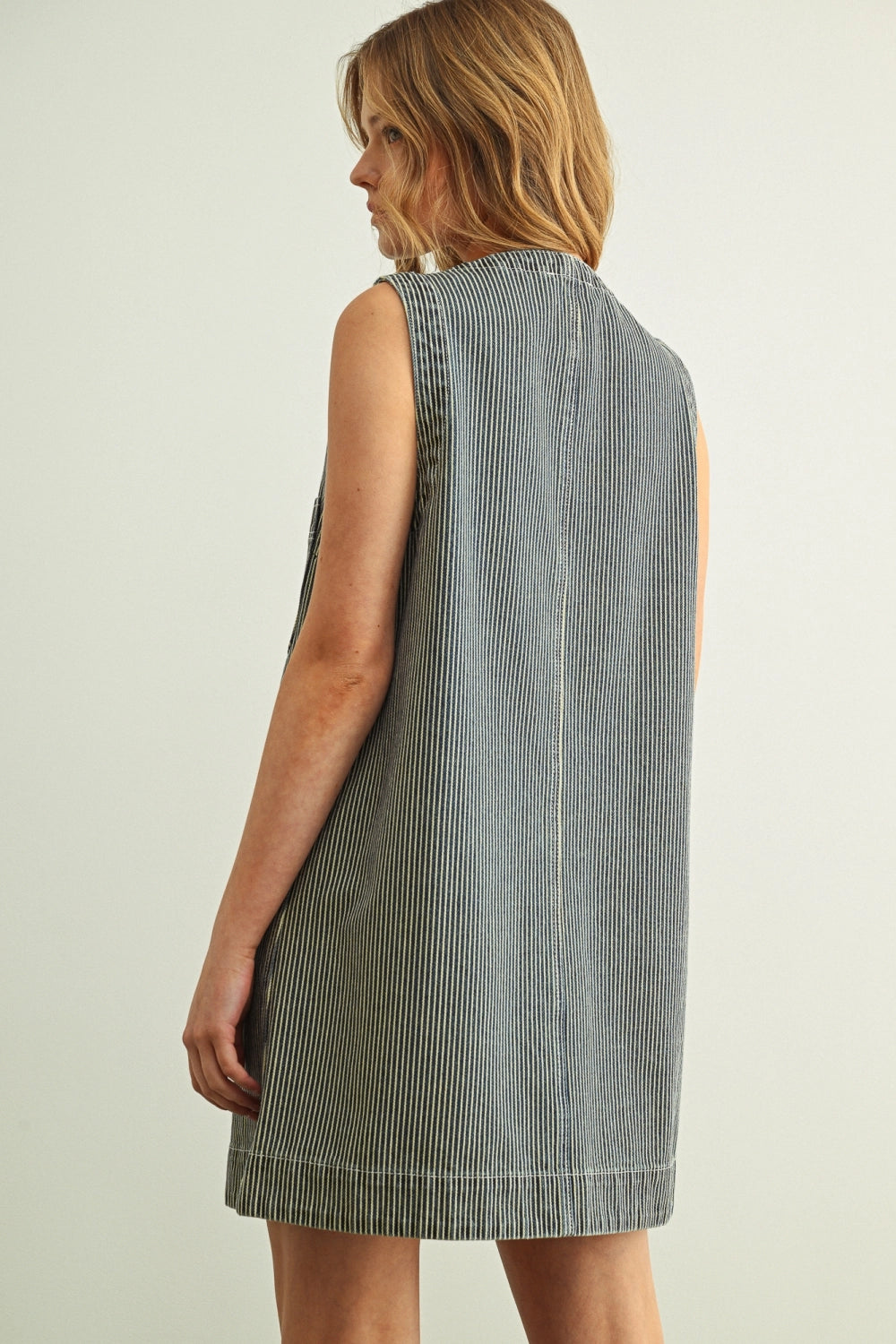 Woman wearing a sleeveless striped dress against a plain background