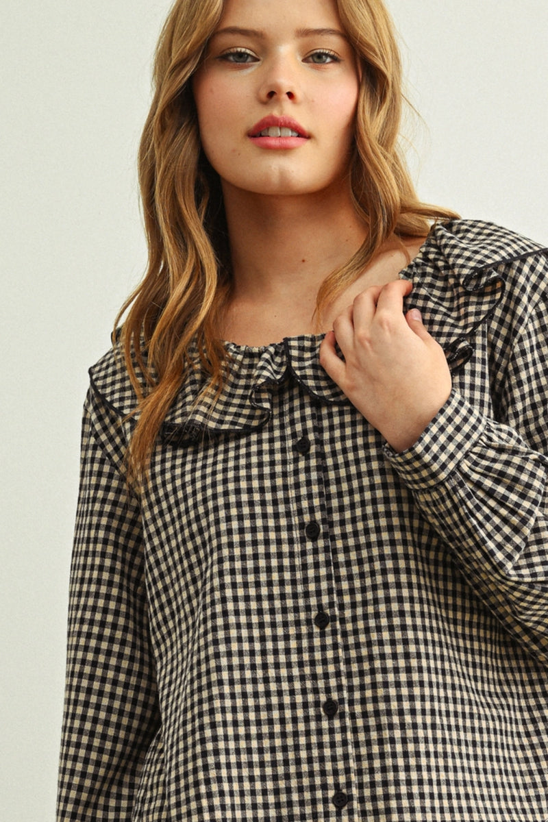 Woman wearing a black and white checkered blouse with a ruffled neckline.