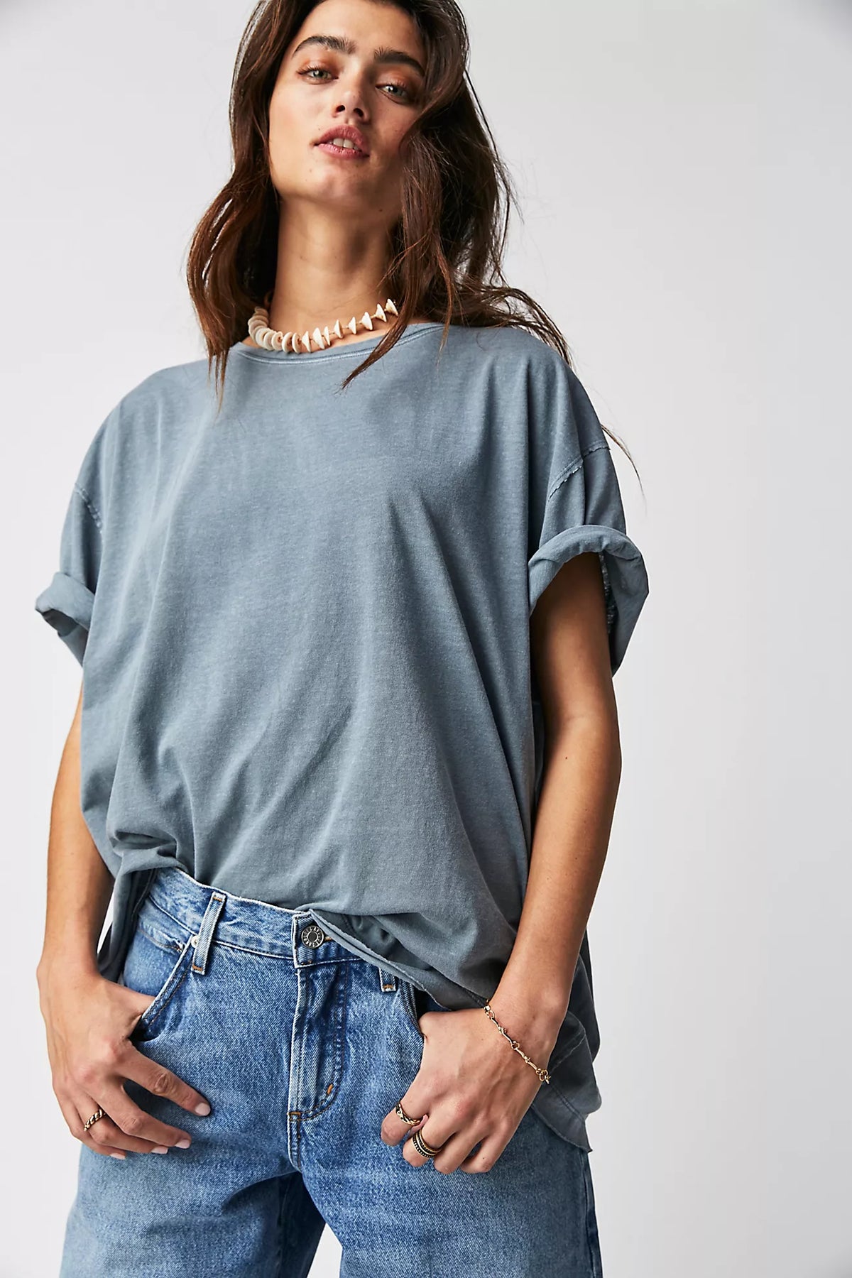 Person wearing a light blue oversized t-shirt and jeans on a white background