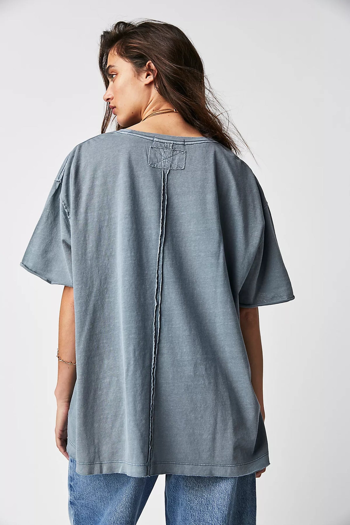 Woman wearing a gray oversized shirt and jeans on a white background
