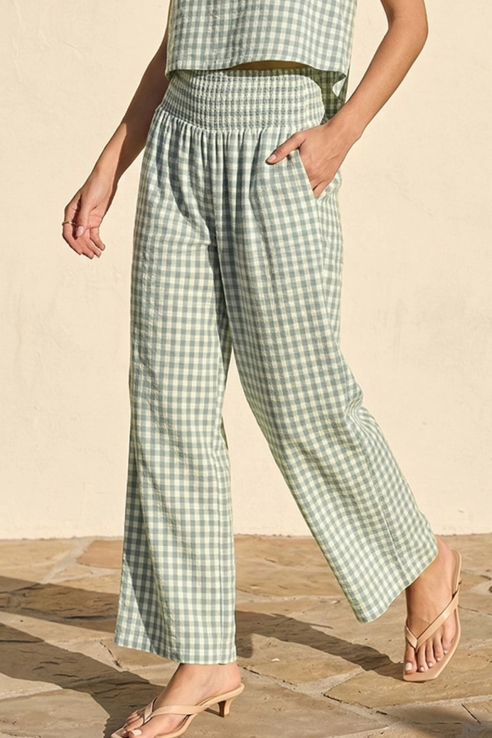 Person wearing green and white checkered pants on a wooden floor.