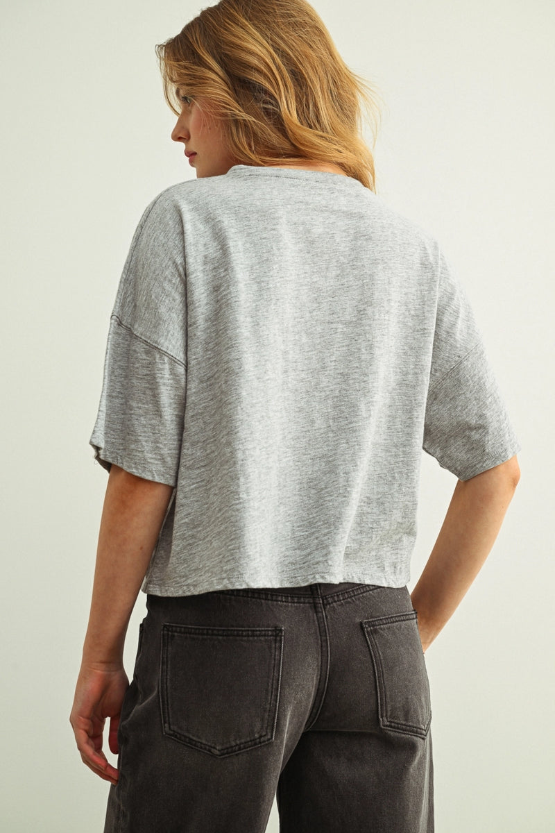 Woman wearing a grey shirt with buttons against a white background.