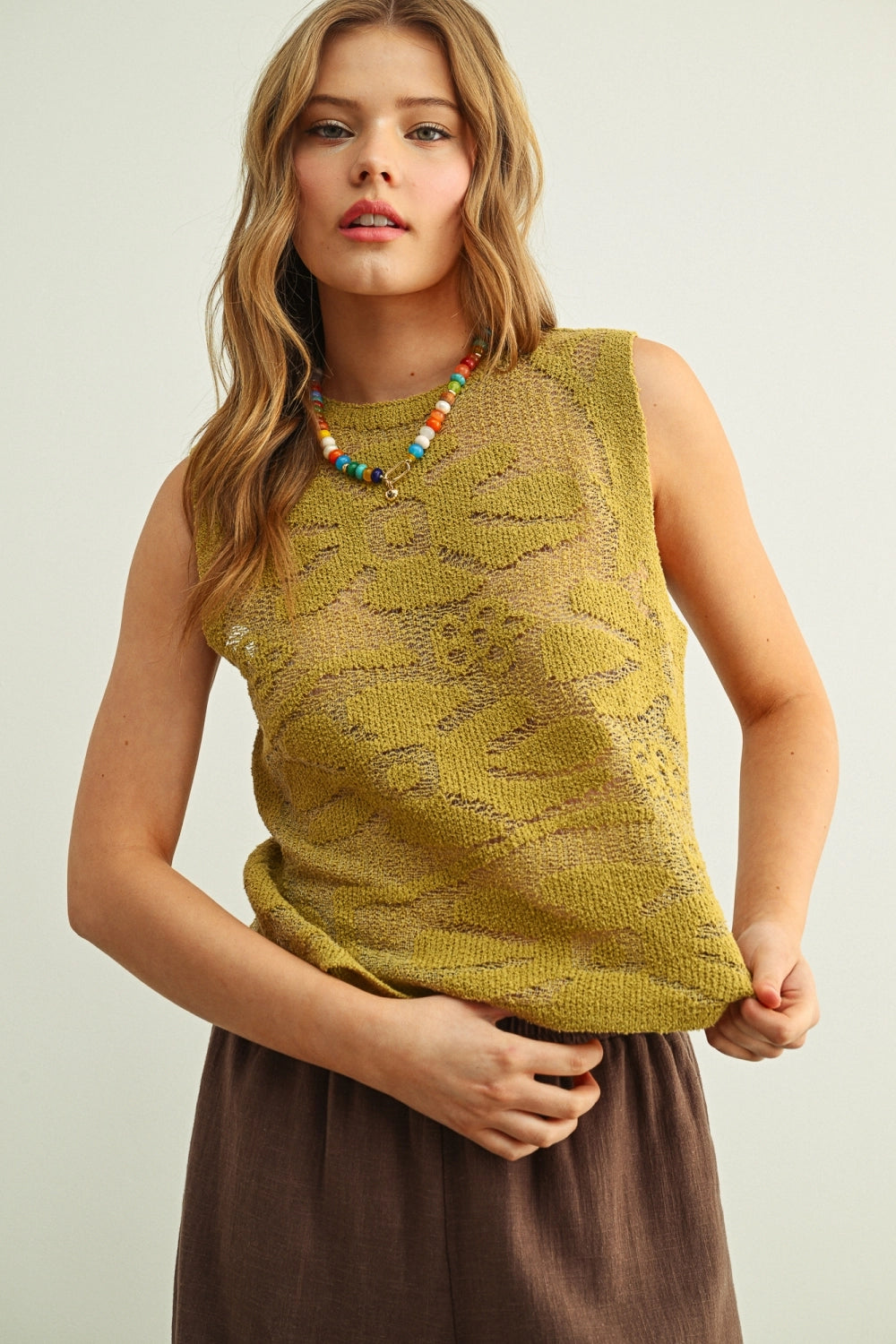 Woman wearing a yellow sleeveless top with a neutral background