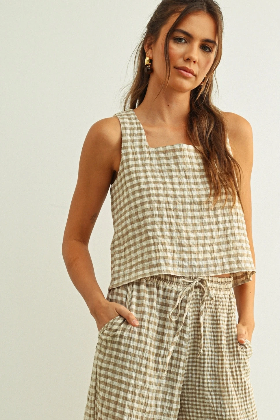 Woman wearing a checkered sleeveless top and pants against a plain background