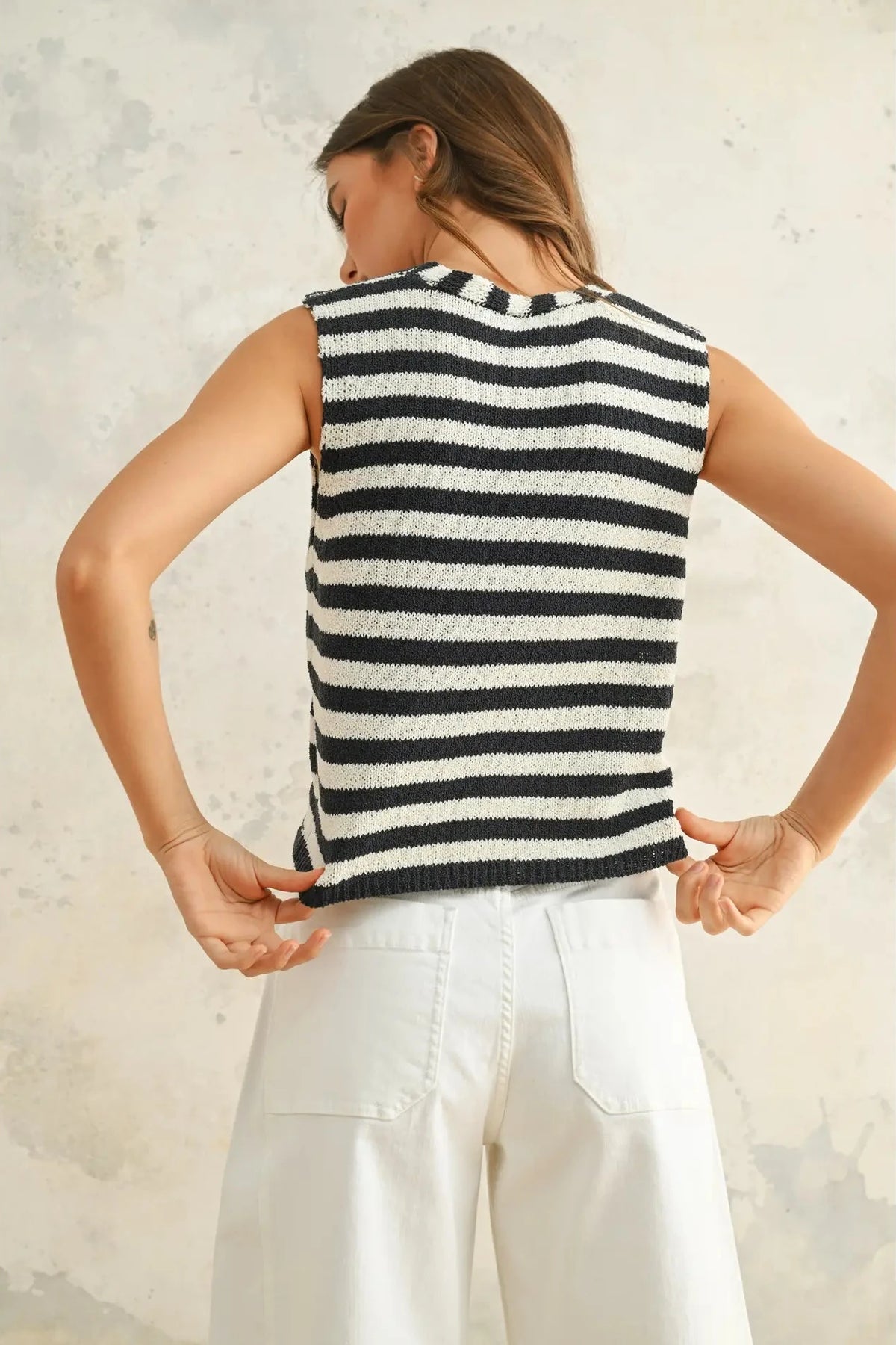 Woman wearing a black and white striped sleeveless sweater against a neutral background