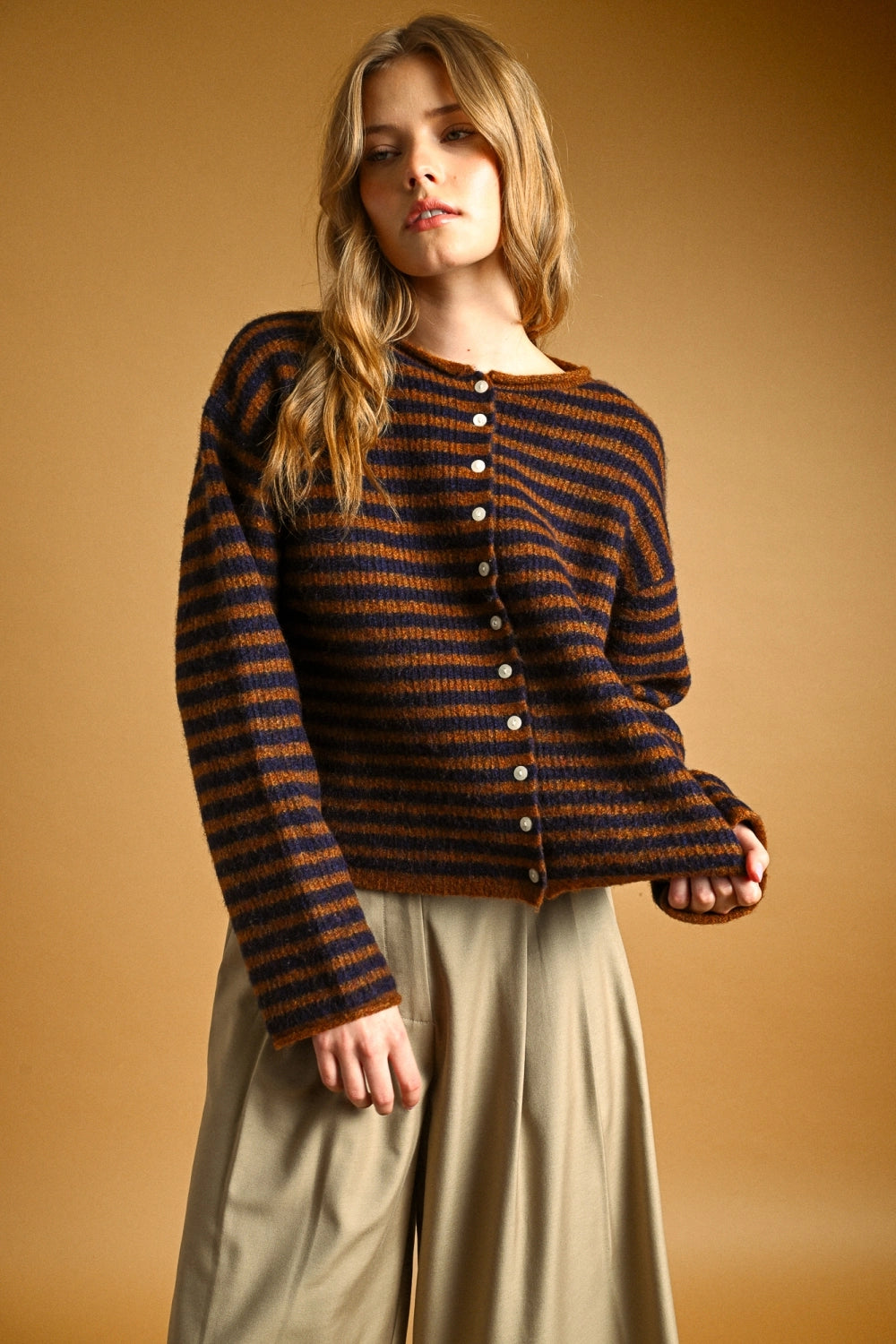 Woman wearing a striped sweater and beige skirt against a beige background