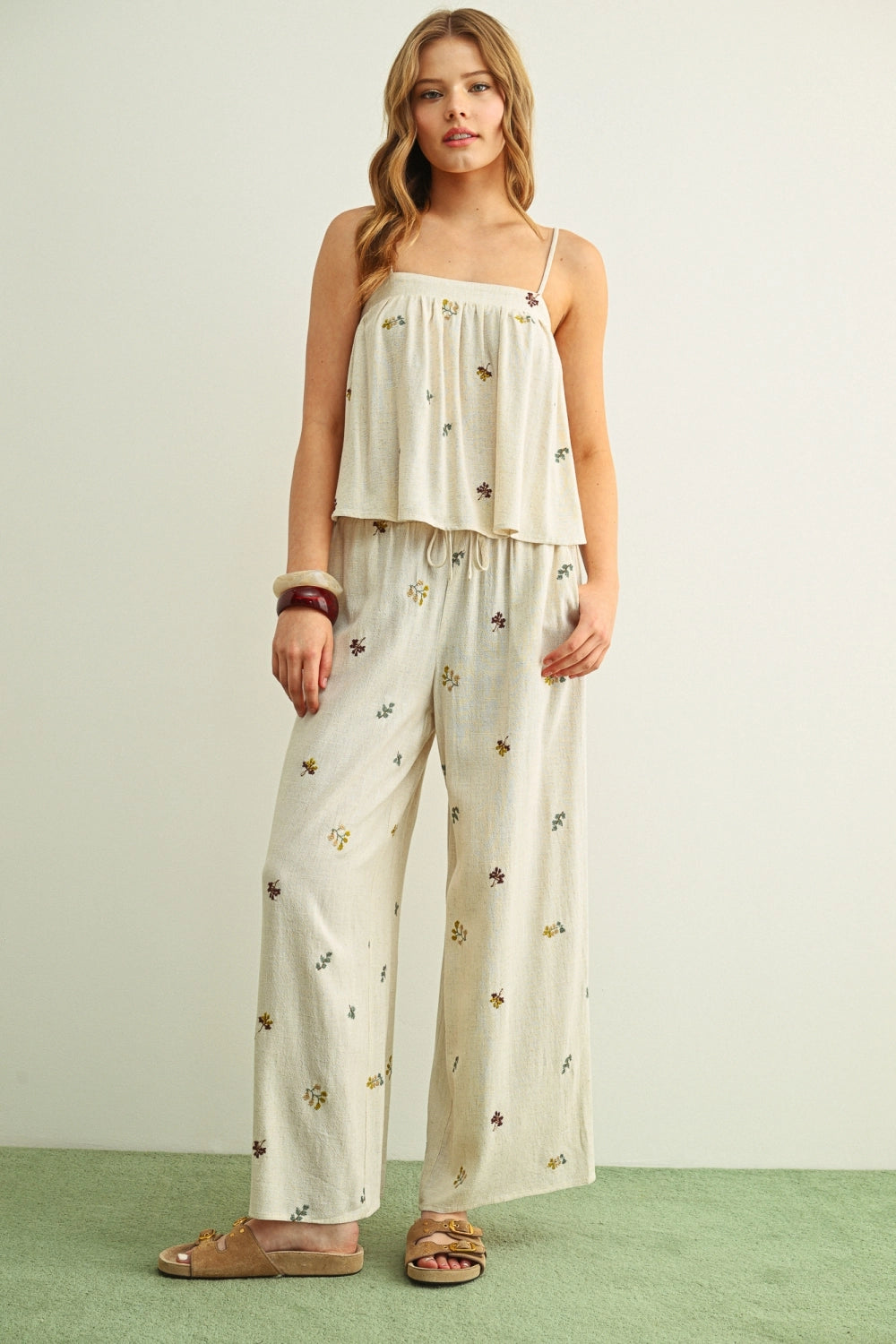 Woman wearing a white floral jumpsuit on a light green background