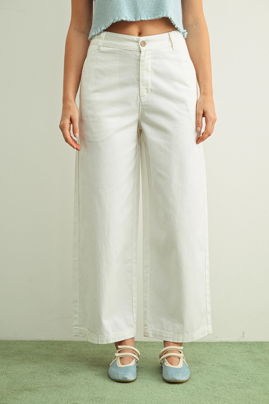 Person wearing white wide-leg pants with a plain background