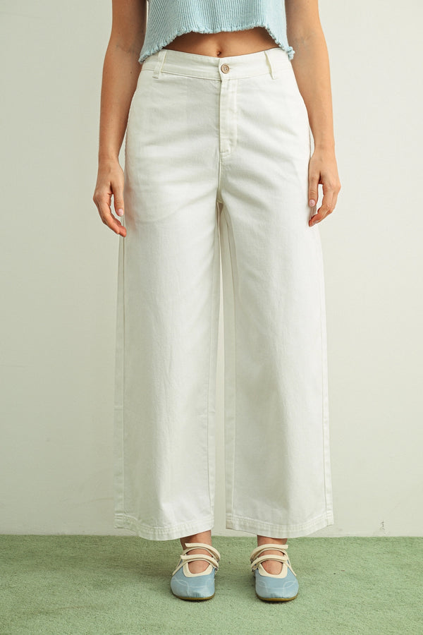 Person wearing white wide-leg pants with a plain background
