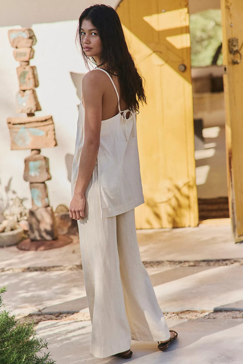 Woman in a neutral colored linen set in front of a house