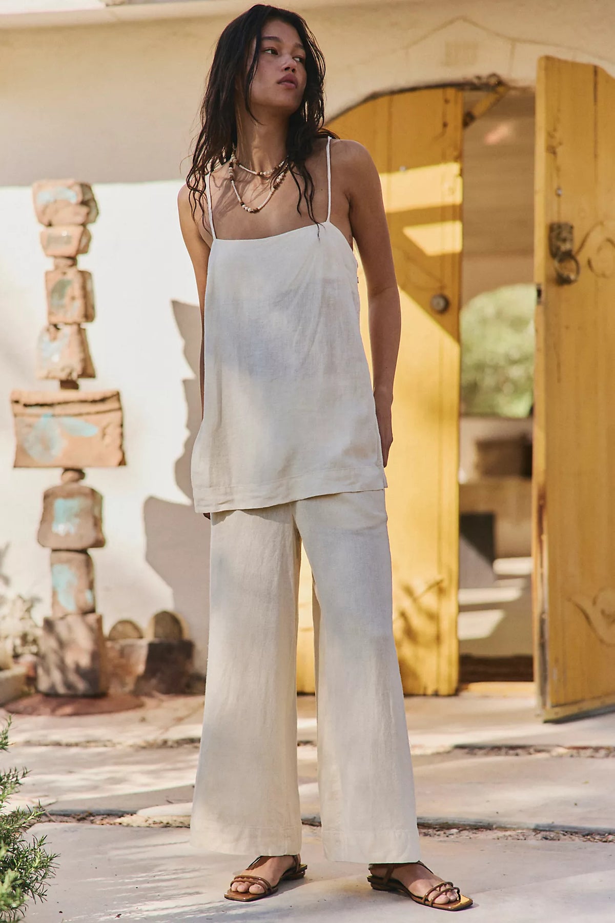 Woman in a neutral colored linen set in front of a house
