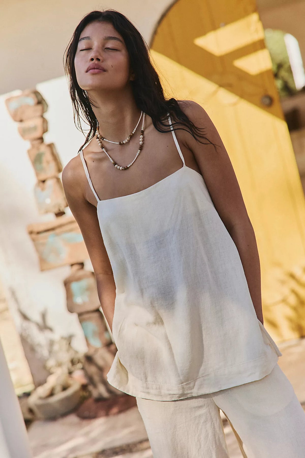 Woman in a neutral colored linen set in front of a house