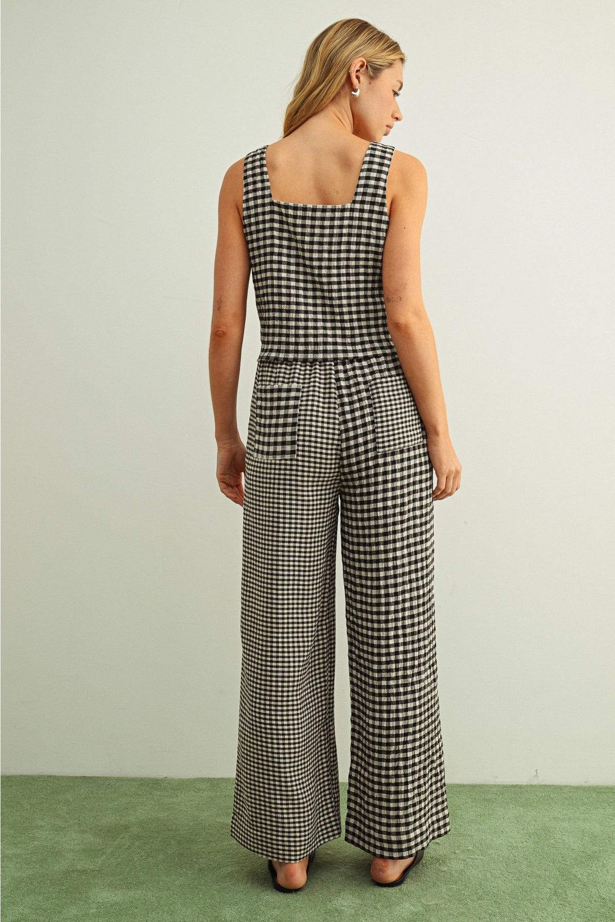 Woman wearing a black and white checkered jumpsuit on a plain background