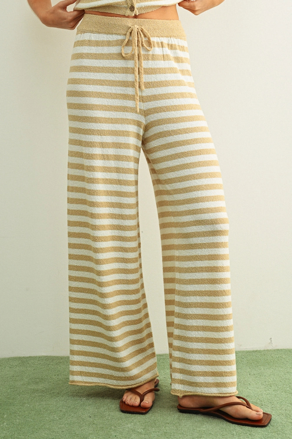Person wearing beige and white striped pants on a plain background