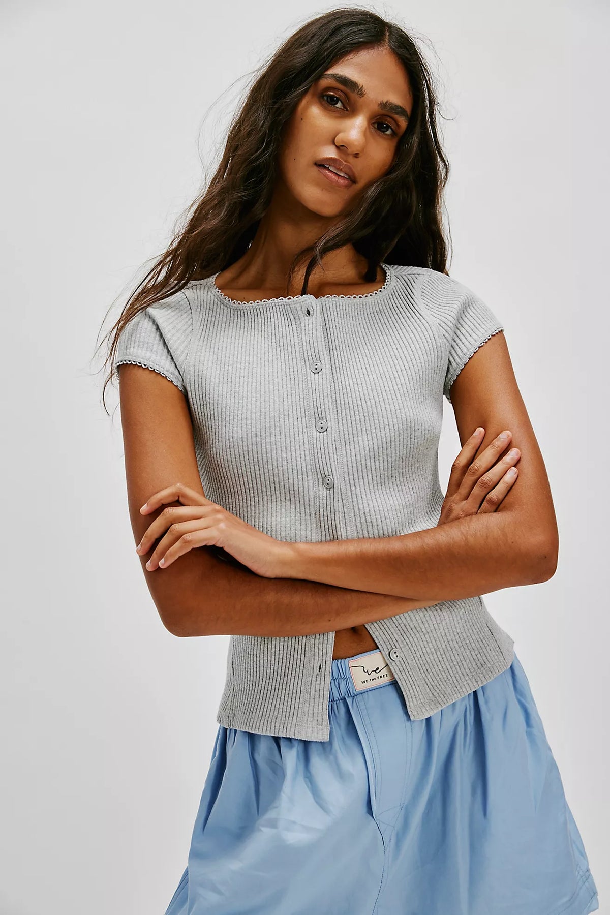 Woman wearing a gray ribbed top and light blue shorts against a white background