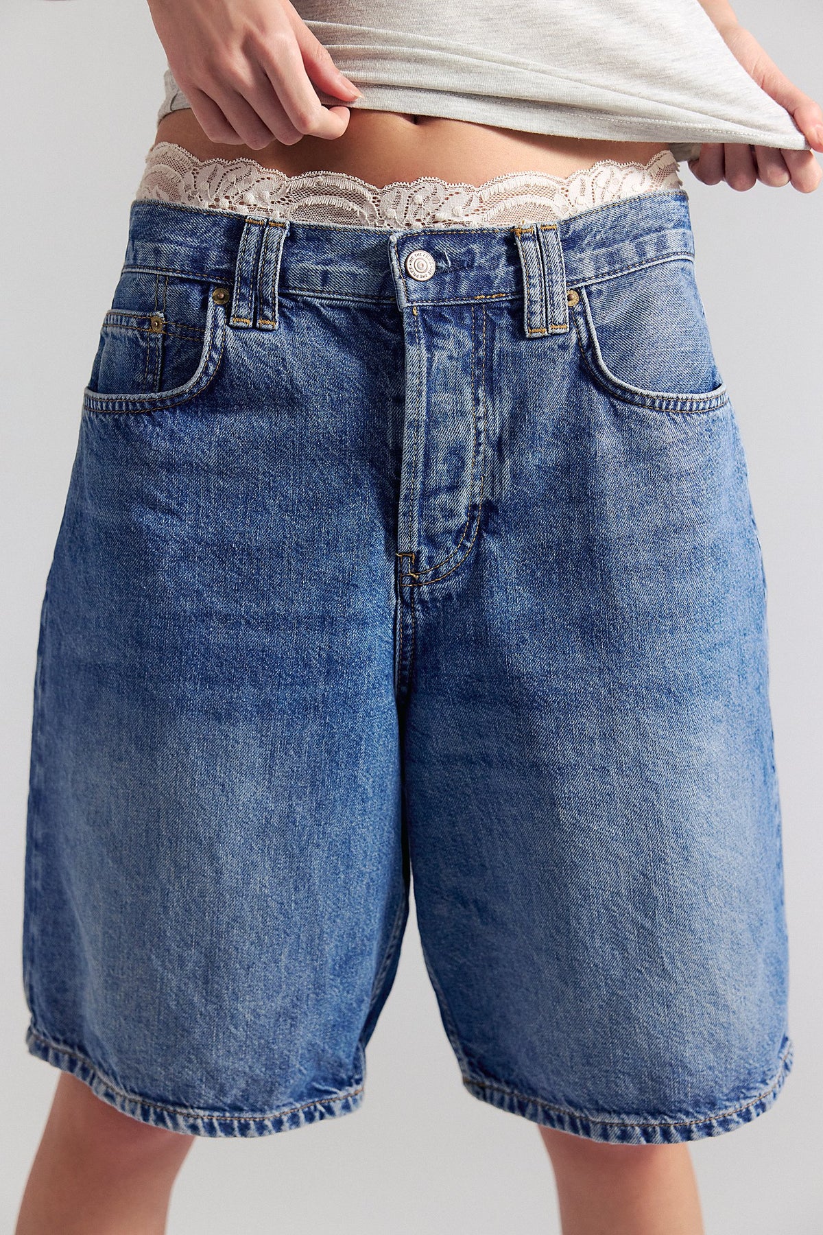 Blue denim shorts worn by a person on a plain background