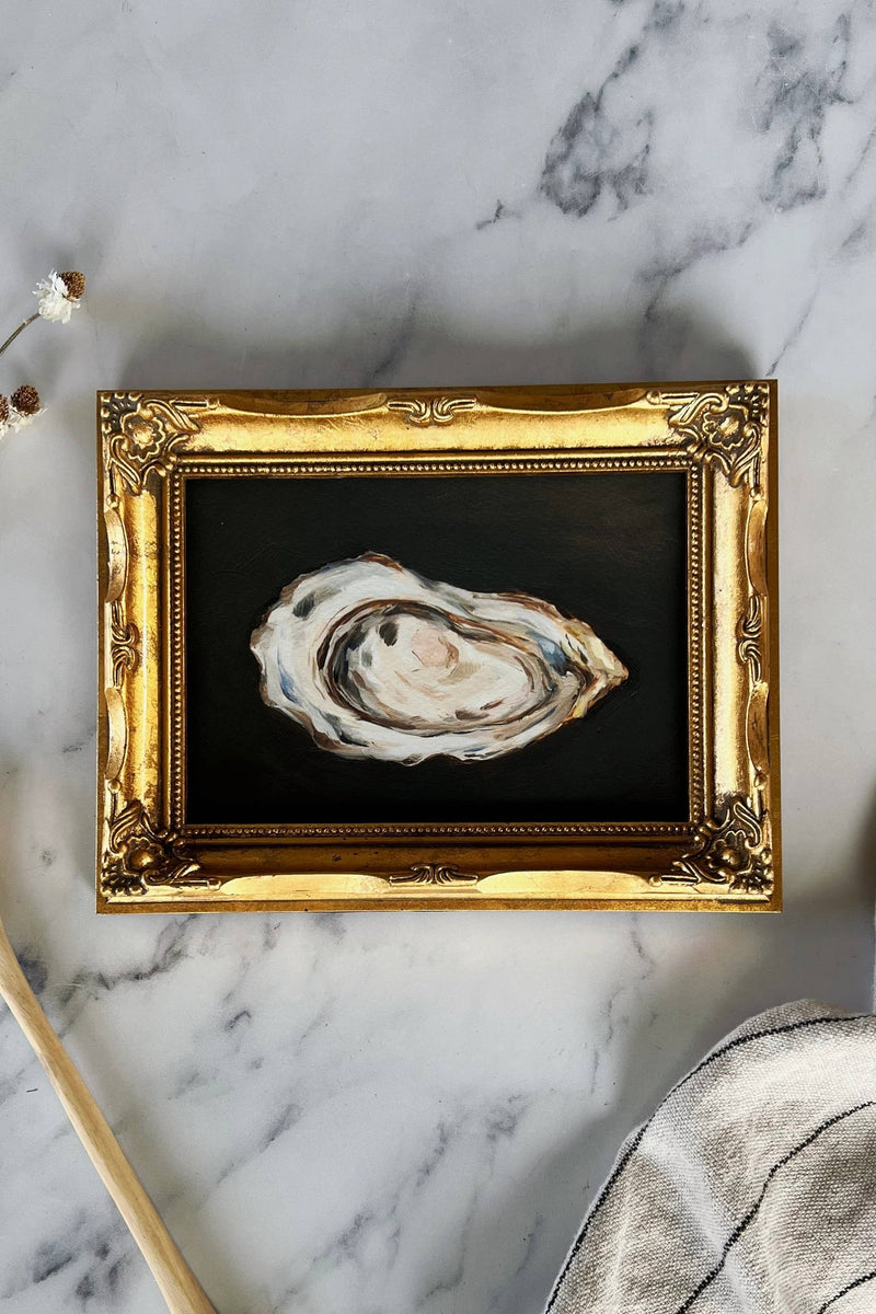 A framed Giclée print of an oyster on a marble surface.