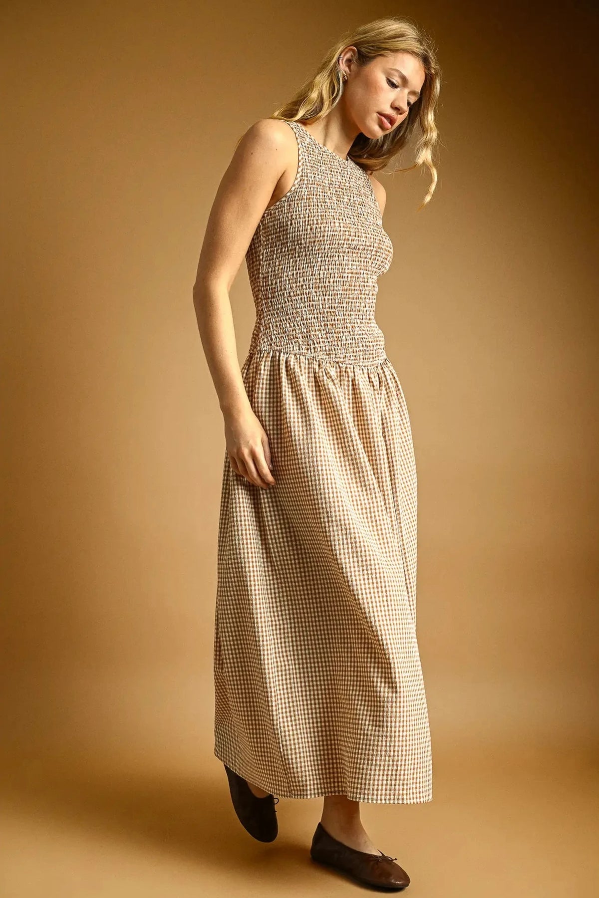 Woman wearing a checkered dress against a beige background
