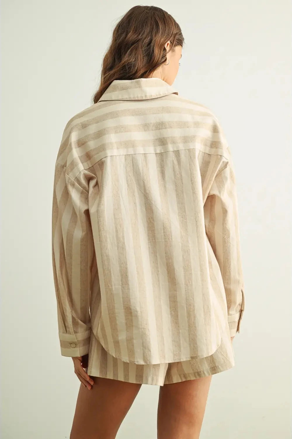 Person wearing a beige and brown striped shirt with shorts on a light background