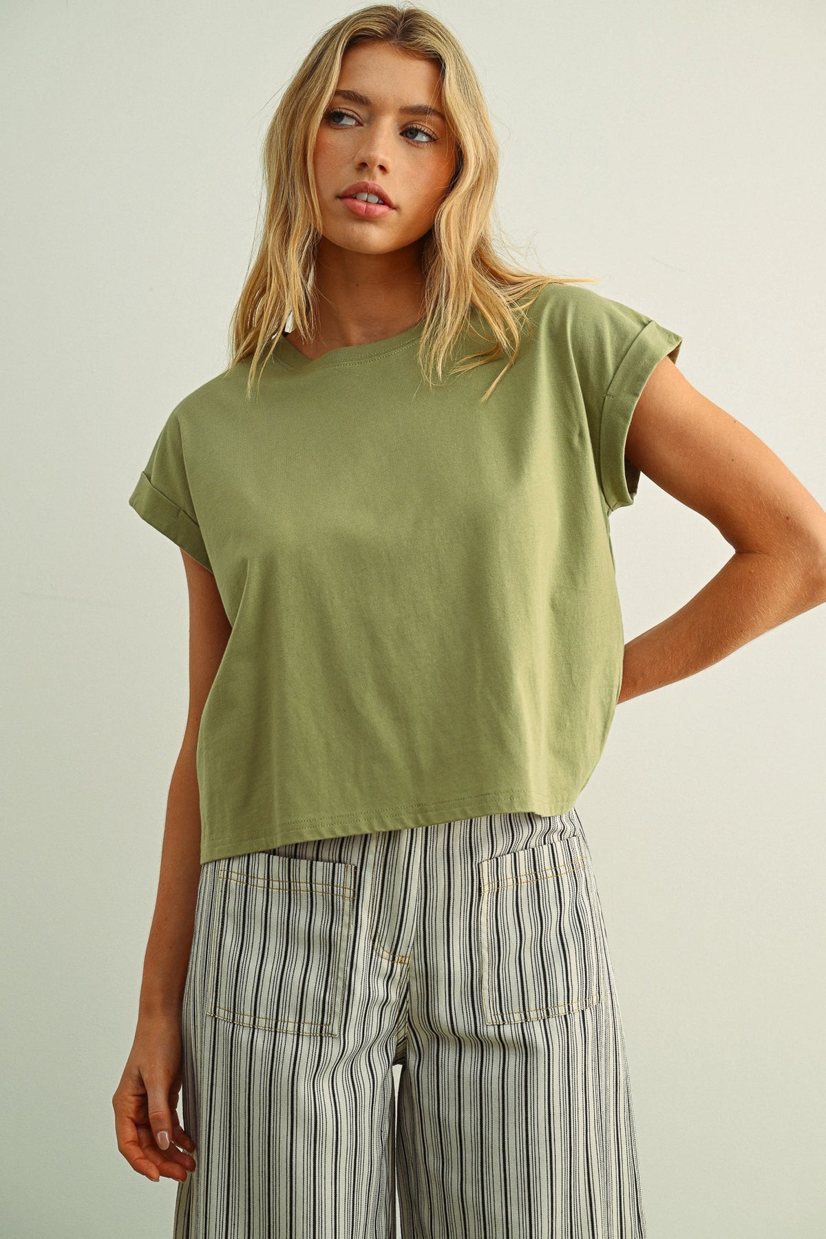 Woman wearing a green top and striped pants against a plain background