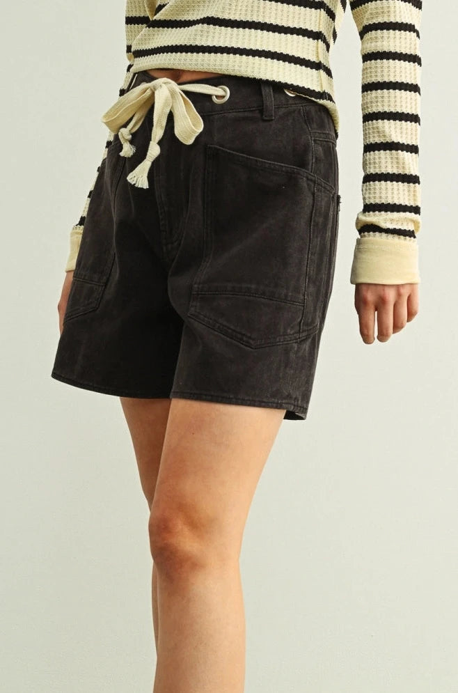 Person wearing black shorts and brown sandals on a green floor with a white background