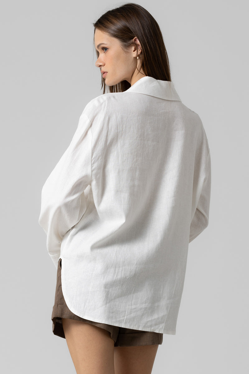 Woman wearing a white oversized shirt against a gray background