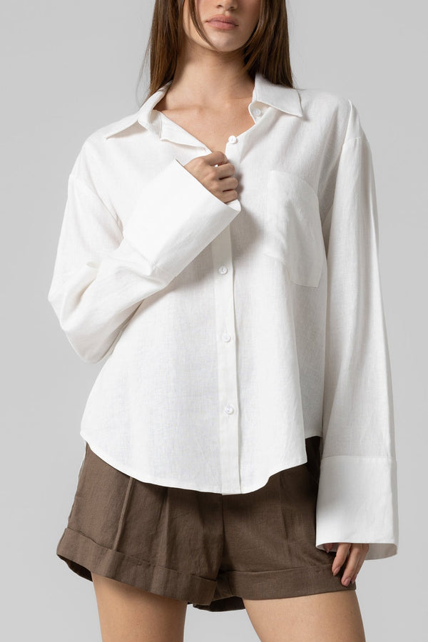 Woman wearing a white shirt and brown shorts on a gray background