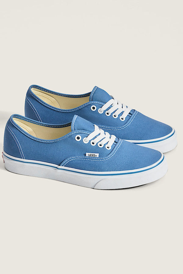 Pair of blue sneakers with white soles on a light gray background