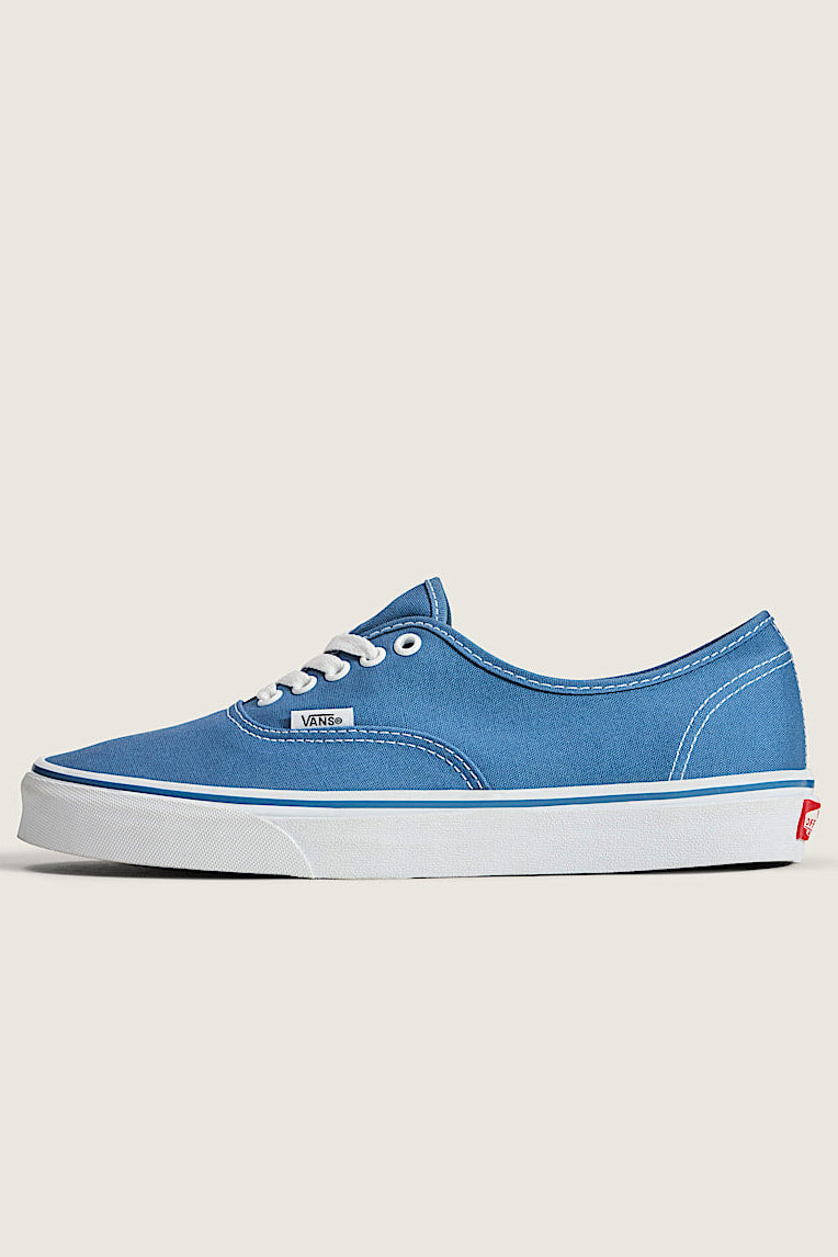 Blue sneaker with white sole on a light gray background
